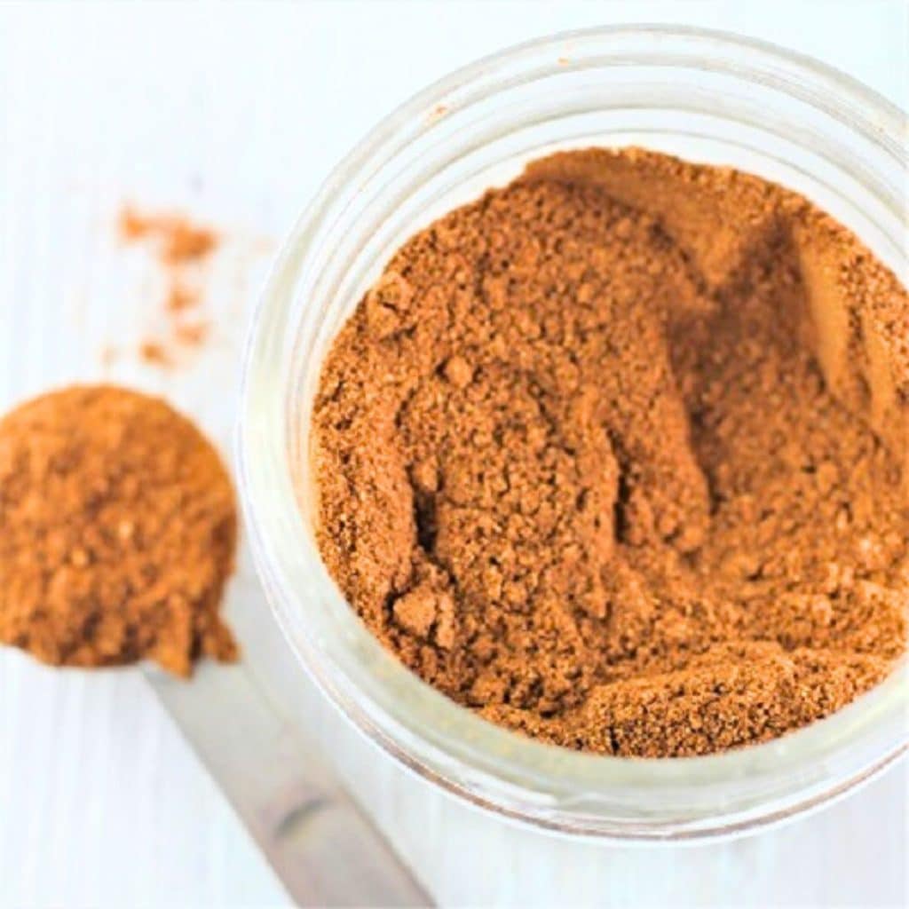 a mason jar filled with homemade pumpkin pie spice with a measuring spoon on the side
